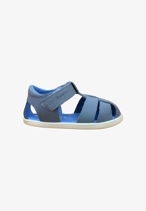 Sandalia azul para niño pequeño con puntera cerrada, tira de velcro y suela de goma blanca, hecha de material de cuero suave.