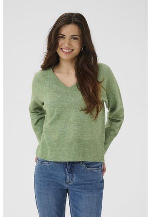 Lysegrøn V-hals sweater lavet af blødt strikmateriale, med ribbede kanter og ærmekanter, kombineret med blå denimjeans. Enkel design.