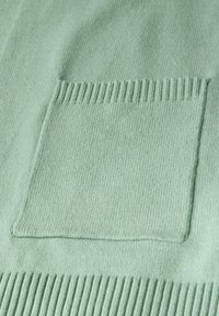 Světle zelený svetr s texturovaným pletením, výraznou čtvercovou kapsou a žebrovanými okraji dole a na rukávech.