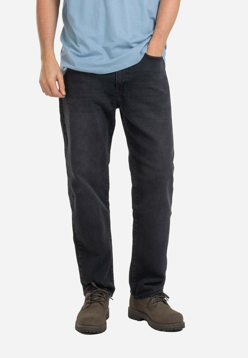 Dunkelgraue Jeans aus Denim mit geradem Schnitt, Fünf-Taschen-Design, kombiniert mit braunen Schnürstiefeln und einem hellblauen T-Shirt.