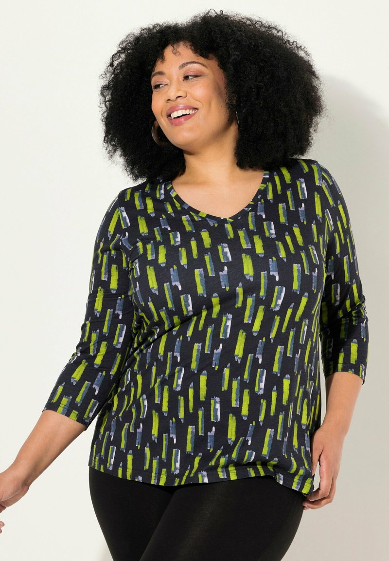 Svart topp med V-ringning och trekvartsärmar. Mönstret har vertikala gröna, blå och vita ränder på en mörk bakgrund. Mjuk tyg.