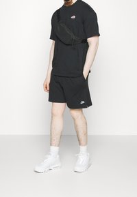 Black Nike t-shirt with logo, black shorts with logo, and white sneakers. The t-shirt has a round neckline and relaxed fit.
