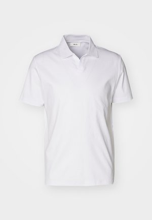 Valkoinen lyhythihainen polo-paita, jossa on kaulus ja pieni etiketti kaula-aukon sisäpuolella, yksinkertaista taustaa vasten.