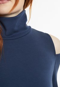 Navyblaues Rollkragenshirt aus weichem Stoff, mit einem offenen Schulterdesign, glatter Textur und minimalen Nähten.