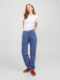Jeans de ganga azul com um ajuste descontraído, cintura alta e design de cinco bolsos. Combinados com uma t-shirt branca justa e sapatilhas vermelhas.