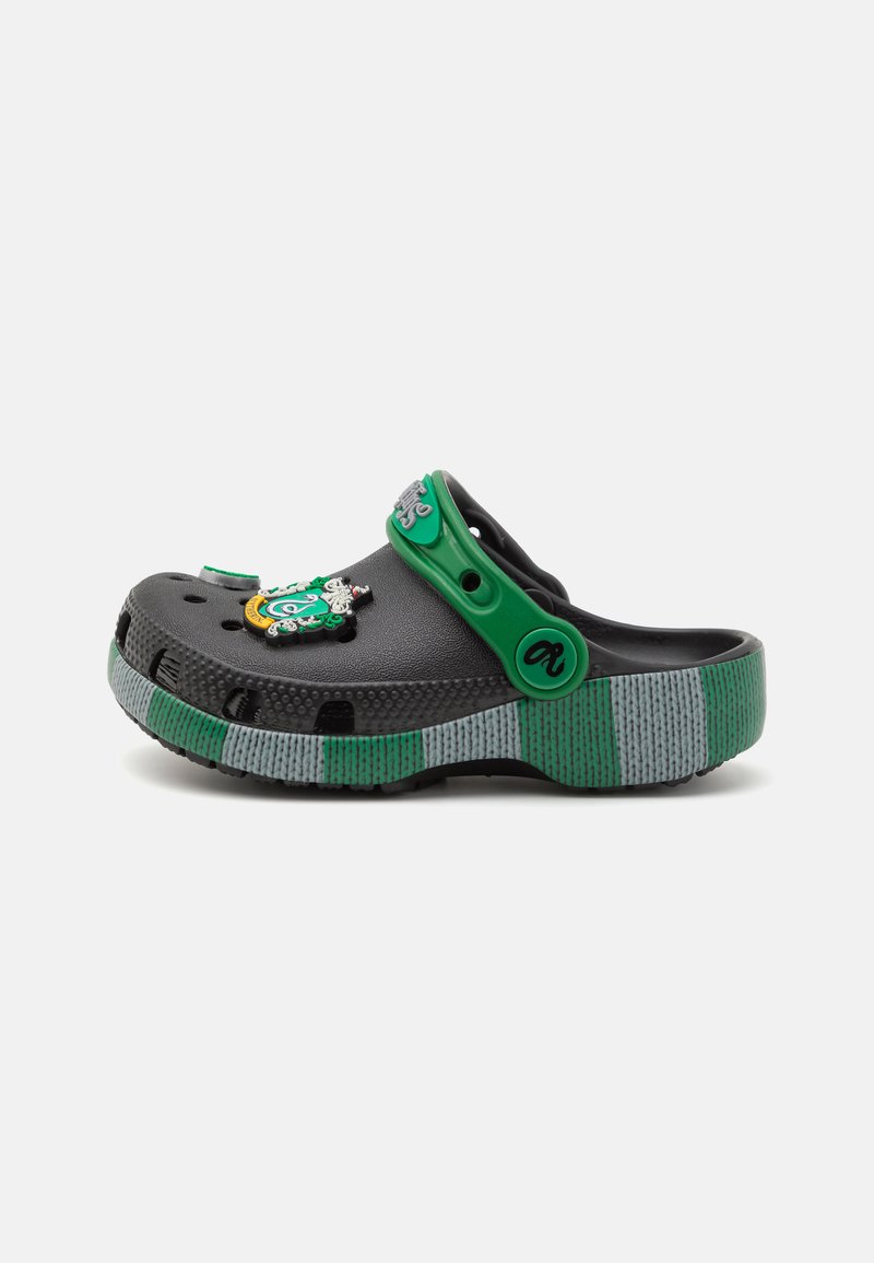 Black clog with a green strap and accents, featuring a textured gray and green striped sole. Includes decorative elements on the front.