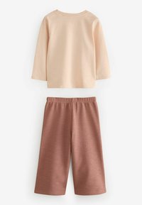 Lys ferskenfarvet langærmet skjorte med rund halsudskæring over rustfarvede shorts i knælængde med elastisk talje og blød tekstur.