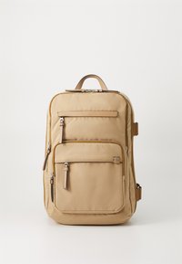 Beige Stoff-Rucksack mit einem oberen Tragegriff, vorderen Reißverschlusstaschen und verstellbaren Trägern, der eine glatte Textur und ein minimalistisches Design aufweist.