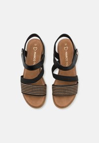 Sandales noires avec une bande texturée noire et dorée à rayures, des brides ajustables et une semelle rembourrée marron. Taille 37 marquée à l'intérieur.