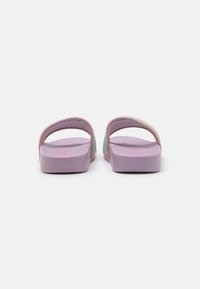 Purple slides with dual adjustable straps. Soft textured soles, flat design, and subtle iridescent accents along the straps.