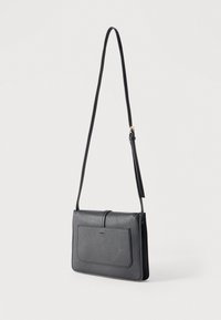 Μαύρο δερμάτινο τσαντάκι χιαστί με εμπρόσθια τσέπη και ρυθμιζόμενο ιμάντα ώμου σε απλό ανοιχτό φόντο.