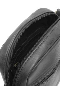 Interno di una borsa in pelle nera con numerosi scomparti con zip e slot per carte. Texture liscia con cuciture rinforzate lungo i bordi.