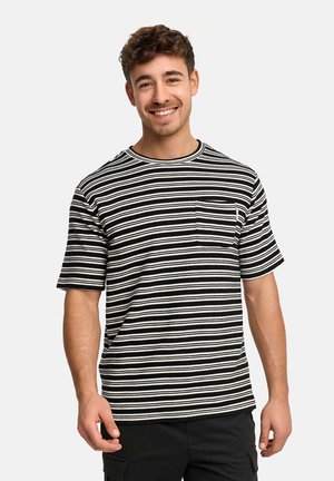 Young man smiling, wearing a black and white horizontal striped short-sleeve shirt with a small chest pocket, standing against a plain background.