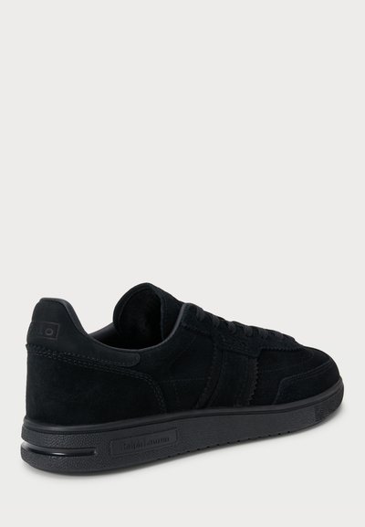 Črne semiš nizke superge z gladkim gumijastim podplatom in teksturiranimi detajli. Imajo vezalko na sprednji strani in embosiran logotip blagovne znamke na peti.