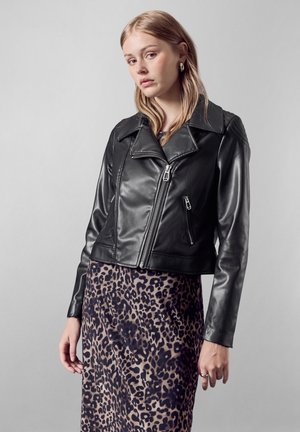 Giubbotto da motociclista in pelle nera con ampio colletto, chiusura con zip frontale e tasche laterali, abbinato a un vestito con stampa leopardo. Texture liscia.