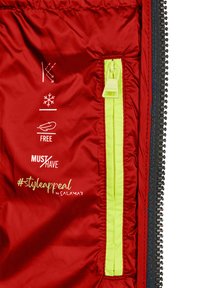 Rote isolierte Jacke mit Innenfutter, das eine neongelbe Reißverschlusstasche und bedruckte Pflegehinweise zeigt. Das Material wirkt glatt und leicht.