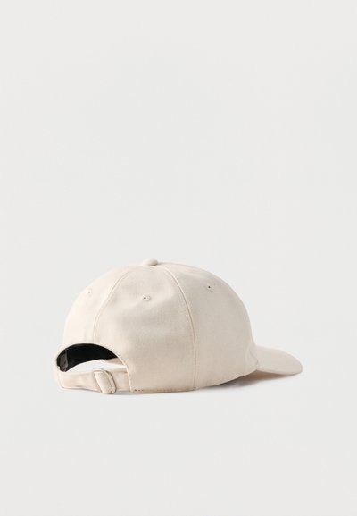 Casquette de baseball en coton beige ajustable, posée à plat, montrant l'arrière avec une bande et une boucle métallique sur un fond blanc uni.