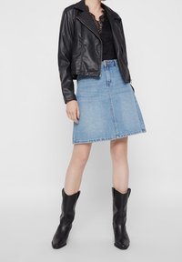 Czarna kurtka motocyklowa z sztucznej skóry, koronkowa bluzka, jasnoniebieska dżinsowa spódnica w kształcie litery A, czarne kowbojskie buty. Elegancki, dopasowany i nowoczesny design.