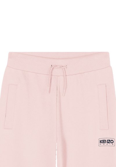 Pantalons de survêtement rose clair en matériau doux, dotés d'une taille côtelée, d'un cordon de serrage et de poches latérales. Comprend un patch logo de la marque.