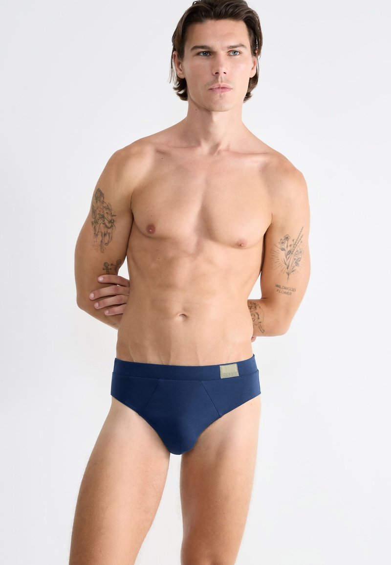 Mørkeblå herreunderbukser lavet af blødt stof, med en glat talje og diskrete syninger. Minimalistisk design uden mønstre.