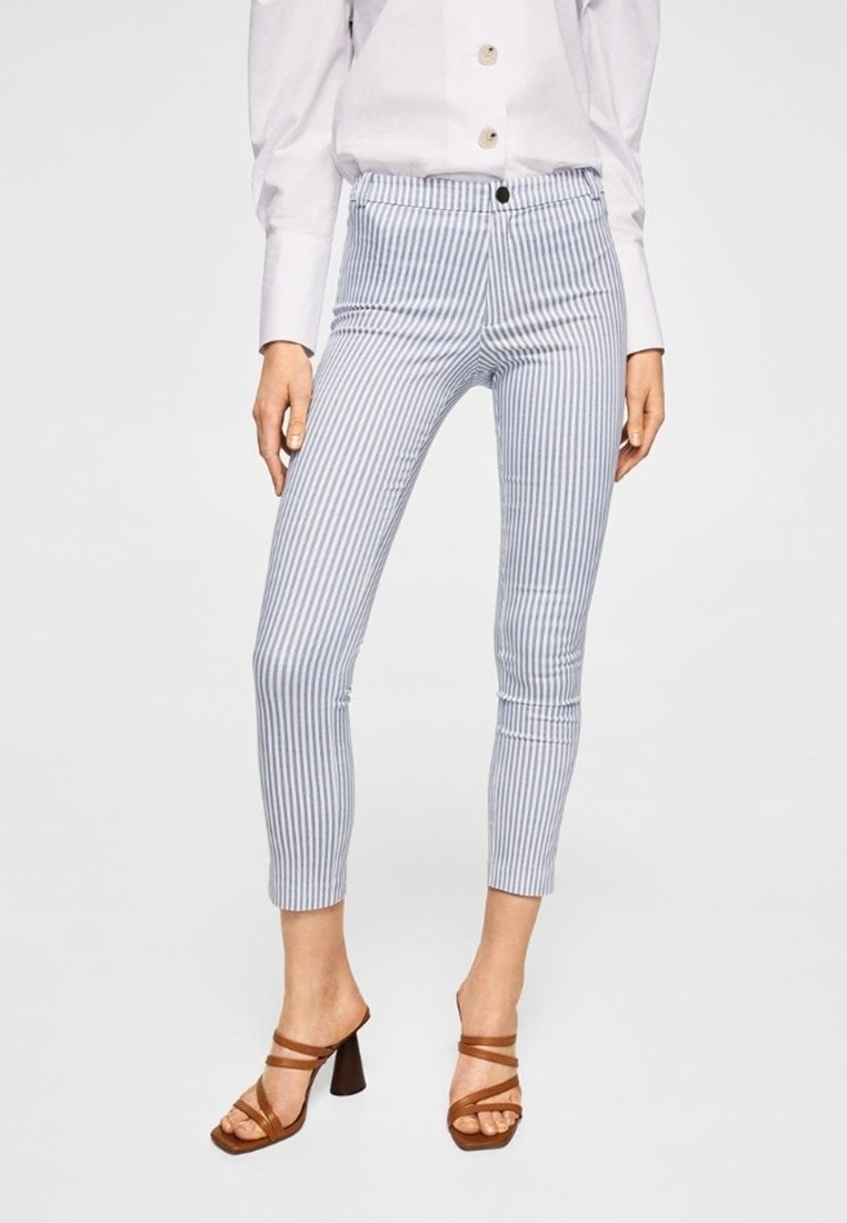 Modré a bílé pruhované skinny kalhoty s vysokým pasem, s předním zapínáním na knoflík a hladkou strukturou. V kombinaci s hnědými sandály na podpatku.