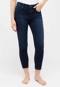 Dark blue denim skinny jeans with a high waist, featuring five pockets and subtle stitching details; fitted through the ankle.