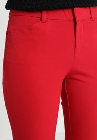 Rode stretch stof broek met een gladde textuur, voorzien van een middelhoge tailleband en voorzakken. Voorpandontwerp met minimale details.