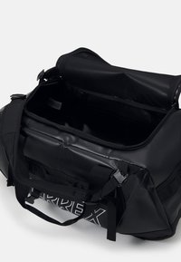 Sac de sport noir avec une fermeture éclair en haut, poche en mesh, sangles réglables et finition brillante. Présente un logo "ARREX" en blanc.