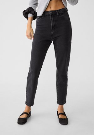 Jeans noirs taille haute avec une coupe droite, texture subtile, design à cinq poches, terminés par un bouton et une fermeture éclair.