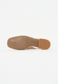 Nude closed-toe shoe sole with embossed floral pattern. Material appears smooth with a textured area at the heel and a flat surface.