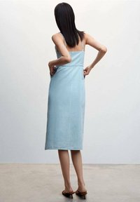 Vaaleansininen denimit edestä polvimittainen mekko ohuiden olkaimien kanssa, tiukka vartalo-osa ja suora leikkaus. Sileä pinta, minimaalinen yksityiskohtaisuus ja siisti helma.