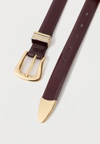Bordová kožená opasok so zlatou kovovou sponou a akcentom. Hladká textúra, zužujúci sa hrot a niekoľko nastavovacích dierok po celej dĺžke.