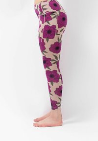 Blumige Leggings mit einem hellbeigen Grundton, die große lila Blumen und grüne Blätter zeigen, aus einem dehnbaren, weichen Stoff gefertigt.
