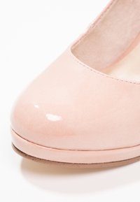 Chaussure pour femme brillante rose clair à talon bas avec bout arrondi et finition lisse, vue en gros plan de face.