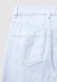 Vista posteriore di pantaloni in denim azzurro chiaro che mostrano una tasca posteriore cucita singolarmente e passanti per cintura sulla vita.