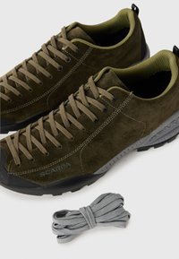 Chaussures en daim vert olive avec bout en caoutchouc noir et lacets gris. Présentent une conception renforcée et une doublure intérieure texturée pour le confort.