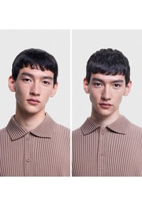 Camicia collare, a coste, in morbido tessuto beige; due bottoni sul colletto; espressione neutra del modello su uno sfondo chiaro.