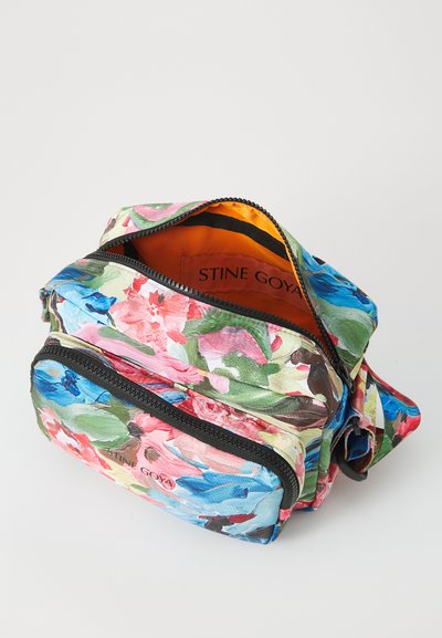 Floral-patterned bag with multiple zippered pockets. Material features soft texture with shades of pink, green, and blue. Interior is orange.