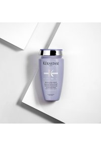 Lavendelfarbene Flasche des Kérastase Blond Absolu Bain Ultra-Violet Shampoos mit silbernem Verschluss auf schrägem weißen Hintergrund.