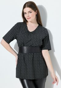 Černý krátký rukáv top s geometrickým šedým vzorem, výstřihem do V a nařaseným pasem zvýrazněným černým páskem z umělé kůže.
