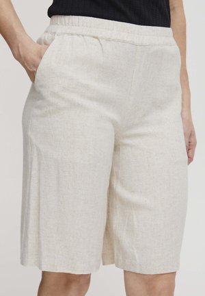 Pantaloni corti in lino beige con una finitura testurizzata, dotati di una vita elasticizzata e tasche laterali. Il design è a lunghezza ginocchio e con vestibilità ampia.