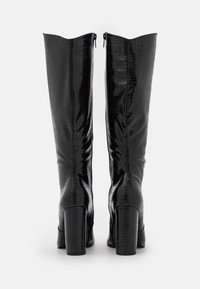 Bottes noires jusqu'au genou avec une texture brillante en faux-crocodile, dotées d'une fermeture éclair à l'arrière et de talons carrés.
