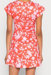 Robe fleurie en corail avec des fleurs roses, manches courtes, corsage ajusté, jupette évasée. Tissu lisse avec un léger éclat, détail de couture dans le dos.