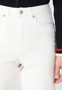 Vita denimjeans med rak bendesign, med knappstängning, framfickor och sömdetalj längs midjebandet.