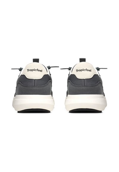 Šedé atletické boty s texturovaným svrškem, bílé mezipodešvi a logem na zadní straně. Obsahují elastické šněrování a poutko pro snadné obouvání.