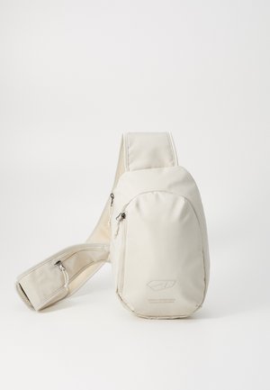 Kremo barve torbica na čez ramo z teksturirano tkanino, ki ima zadrgo na sprednjem žepu in nastavljivim trakom. Minimalistična zasnova z detajlom logotipa.