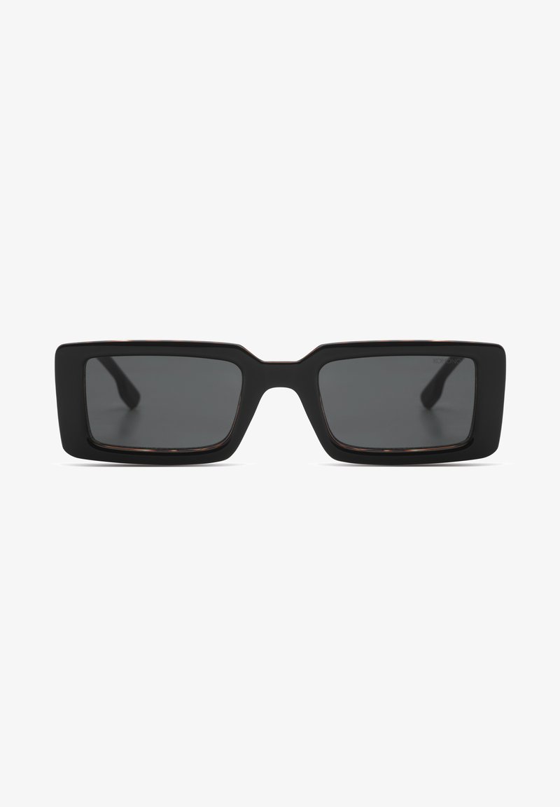 Lunettes de soleil rectangulaires noires avec des montures épaisses et des verres teintés foncés, présentées de face sur un fond blanc.