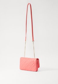 Přebalovaný růžový crossbody batoh s hladkým povrchem a zlatými řetízkovými detaily. Má obdélníkový tvar a jedno nastavitelné ramenní poutko.