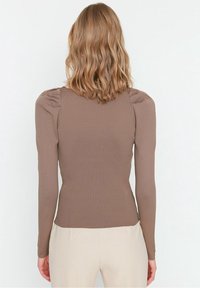 Braunes, geripptes Langarmoberteil mit Puffärmeln, figurbetontem Schnitt und glatter Textur. Rückansicht zeigt eine nahtlose Verarbeitung und einen schlichten Ausschnitt.