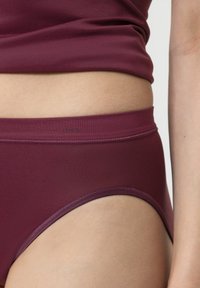 Burgundowe majtki o wysokim stanie, wykonane z elastycznego materiału, o gładkiej strukturze i elastycznym pasie z minimalnym logotypem.